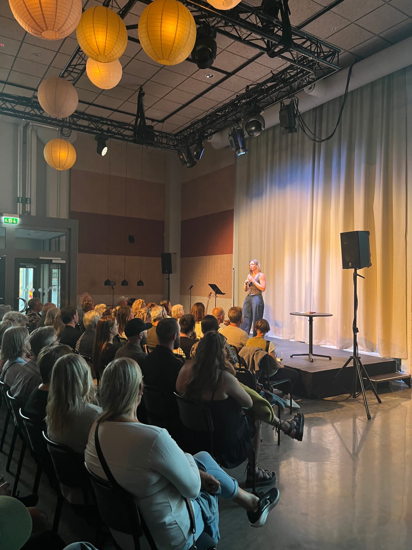 Komiker på scenen sedd snett från publikplats