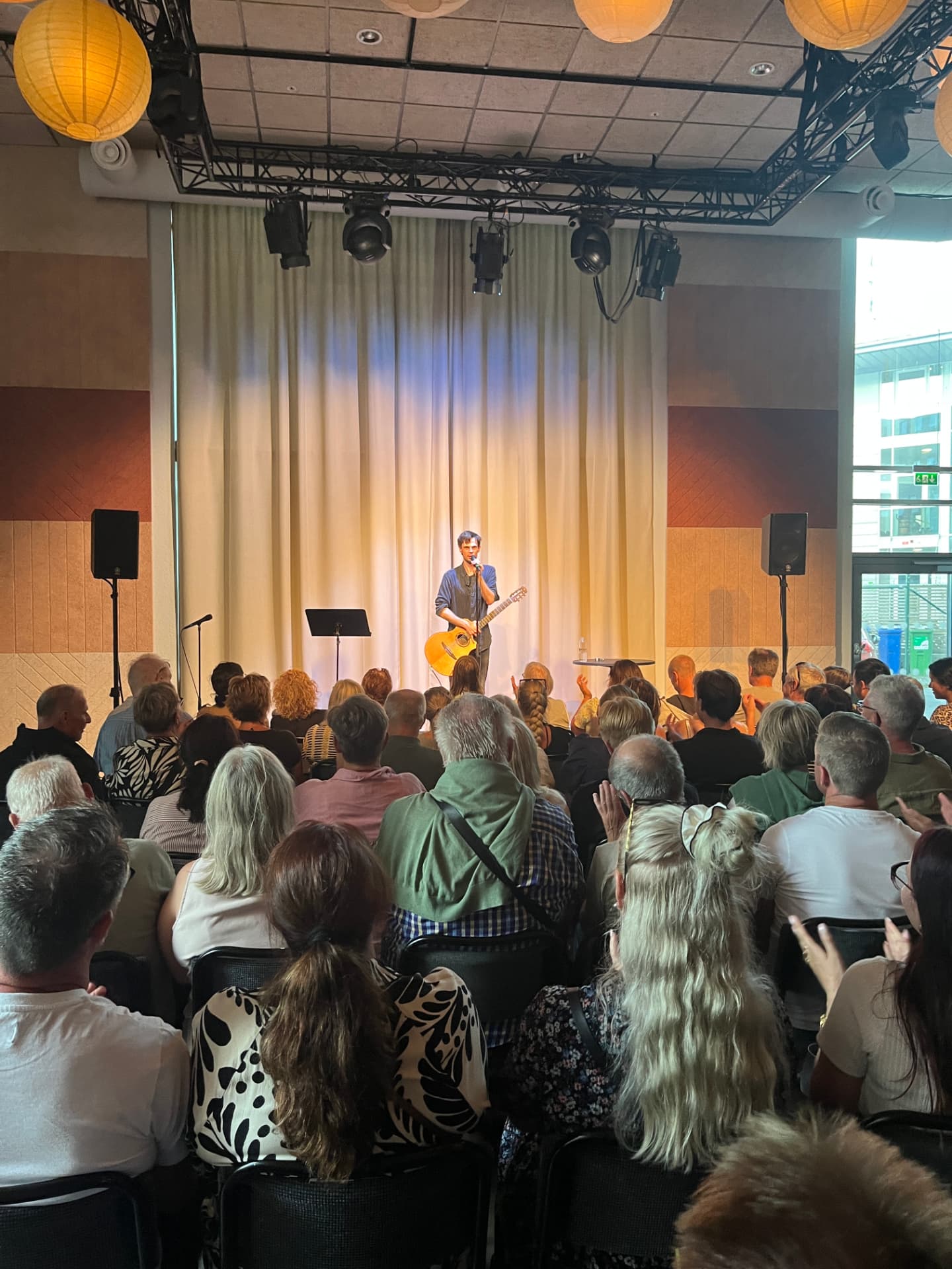 Artist med gitarr på scen i blått och varmt ljus
