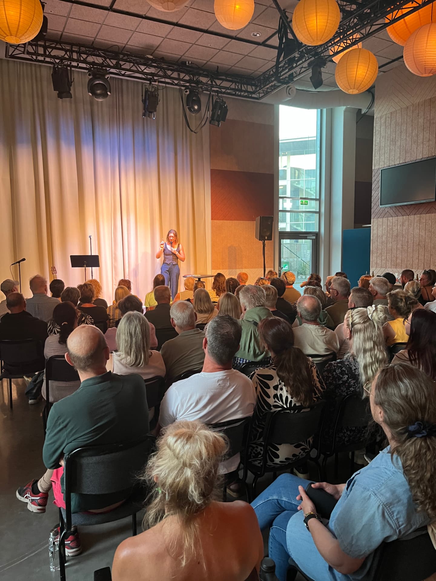 Komiker i spotlight på scen med publik som lyssnar